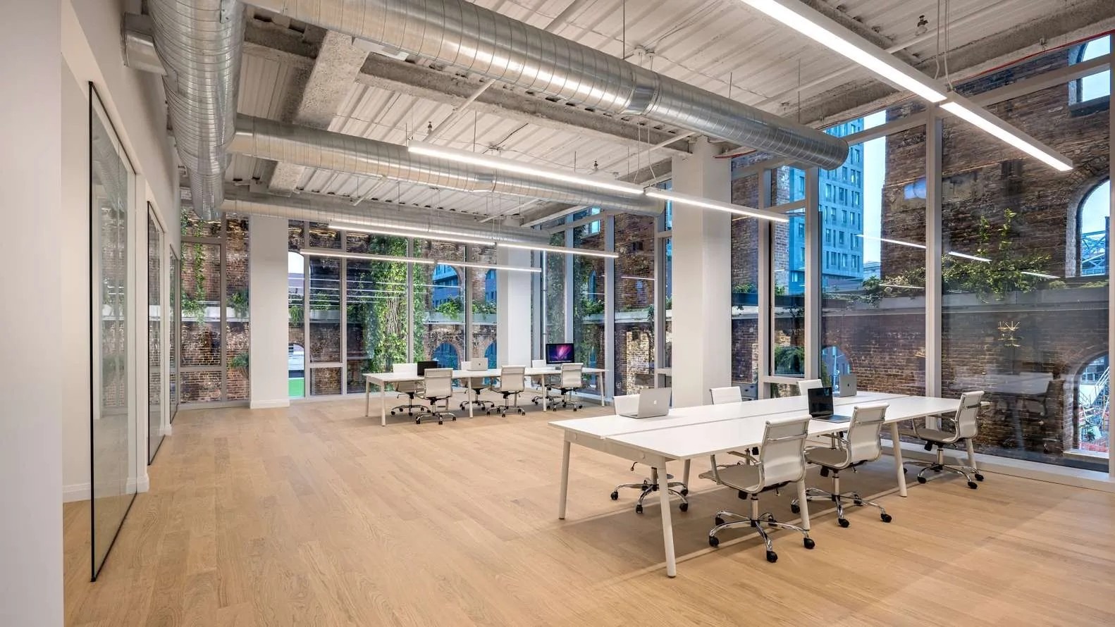 Bright, Modern Office Space Featuring Large Windows, Minimalist Desks, and Light Wood Flooring, Promoting a Collaborative Work Environment.