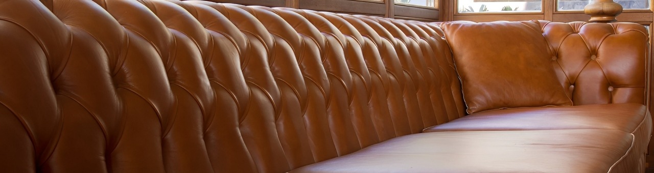 Brown Leather Tufted Sofa With a Smooth, Unembellished Seat, Showcasing a Stylish Design Suitable for a Cozy Interior Space.